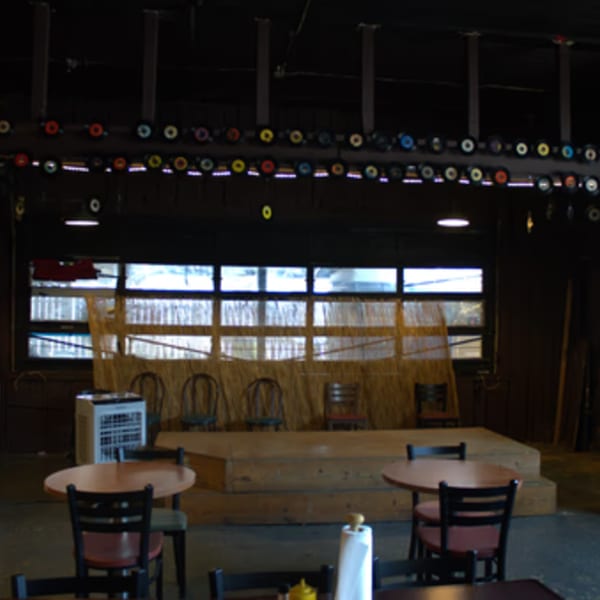 The Service Station Restaurant's interior with a stage, tables, chairs, and record decorations.