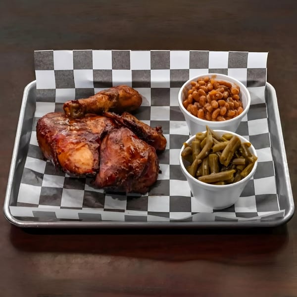 BBQ chicken with baked beans and green beans on a checkered paper-lined tray.