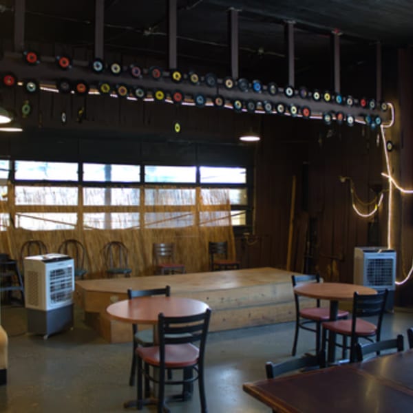 The Service Station Restaurant's interior with tables, chairs, a stage, and records decorating the ceiling.