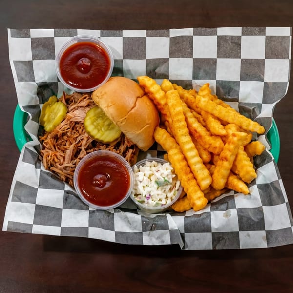 Pulled pork sandwich with pickles, crinkle-cut fries, coleslaw, and two cups of BBQ sauce.