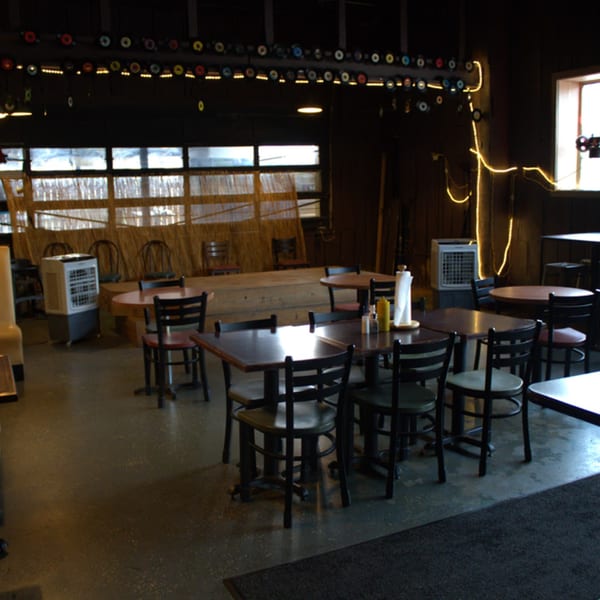 The Service Station Restaurant's dining room with dark tables and chairs, and string lights.